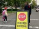 Children using a guarded crosswalk in a residential area on their way to school.