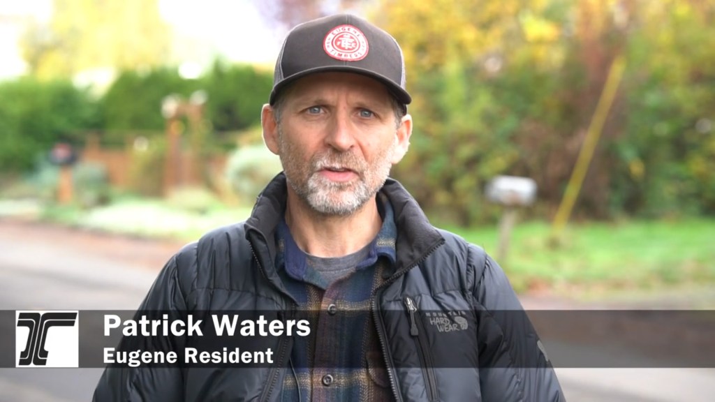 Eugene resident Patrick Waters gives an interview wearing a puffy black coat and a baseball cap.
