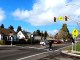 A child on an electric scooter and a pedestrian use a marked crosswalk with a school crossing traffic sign to cross in front of oncoming traffic.