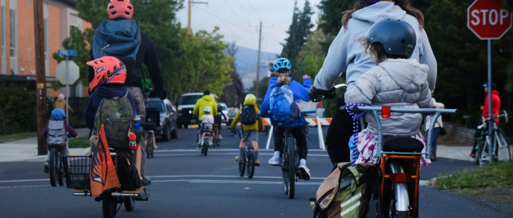 Parents and children riding their bikes to school. Using hand signals to stop at a stop sign in a residential neighorhood.